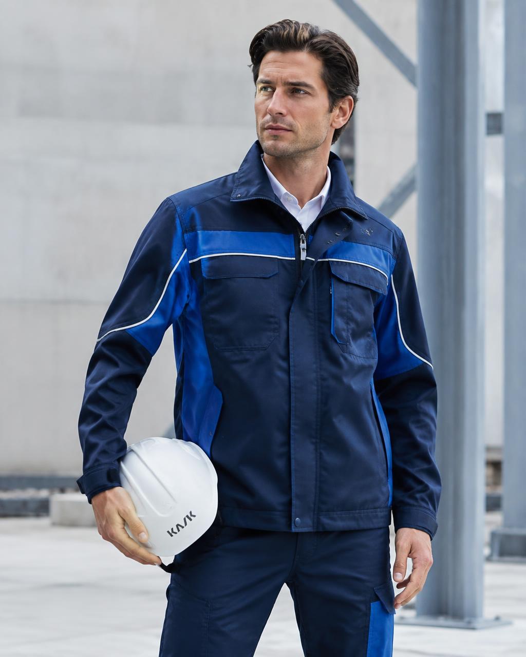 Construction site manager in a custom tailored navy and blue Innovtex work jacket holding a hard hat